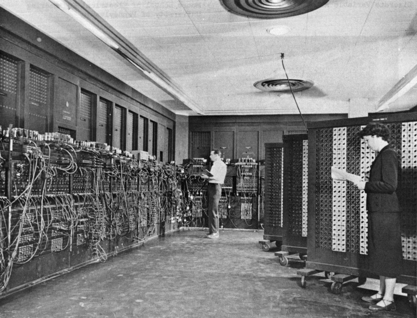 People working beside a room-sized early computer